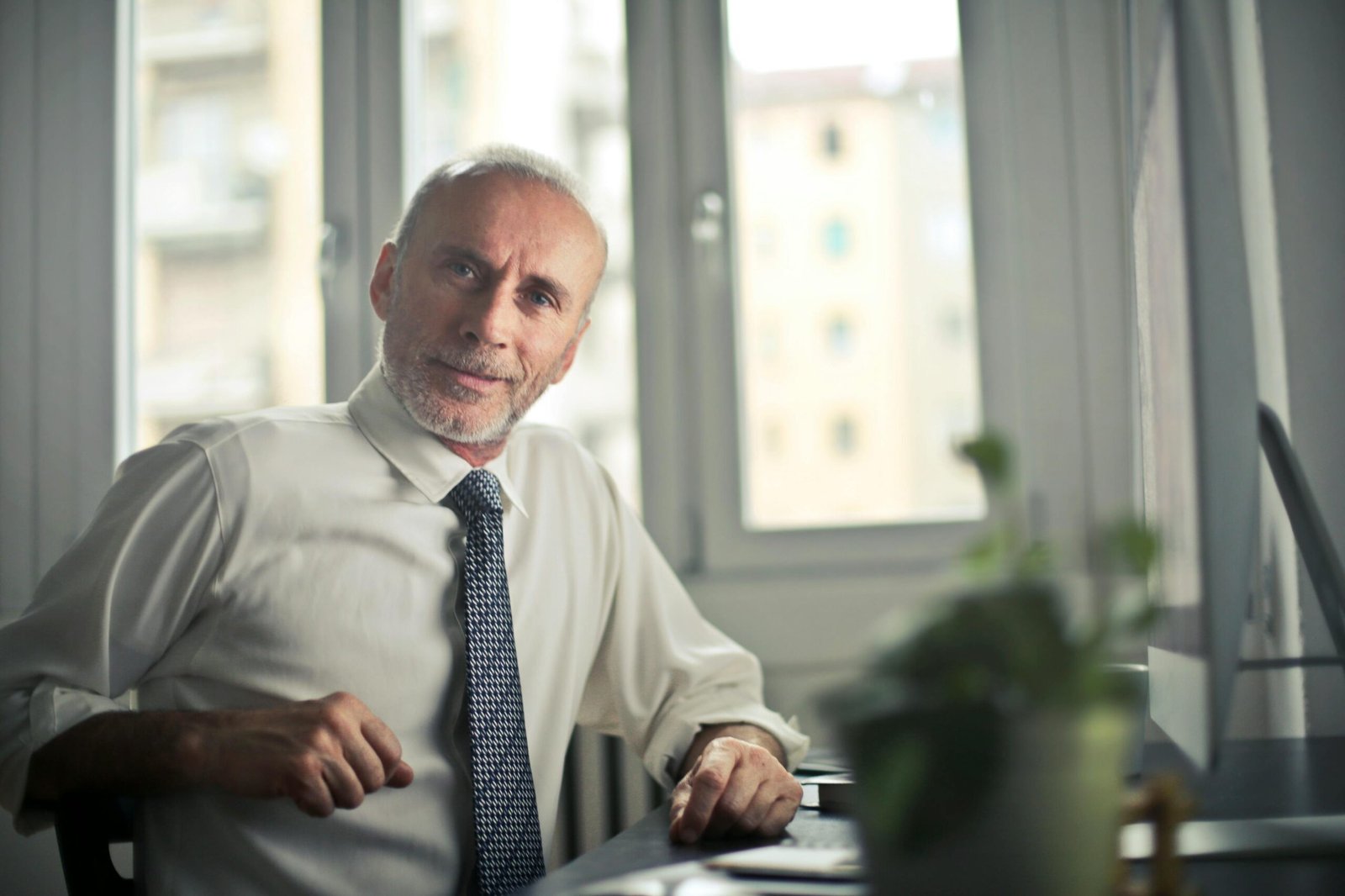 pexels-photo-834863-834863 A mature man in professional attire smiling in an office setting.